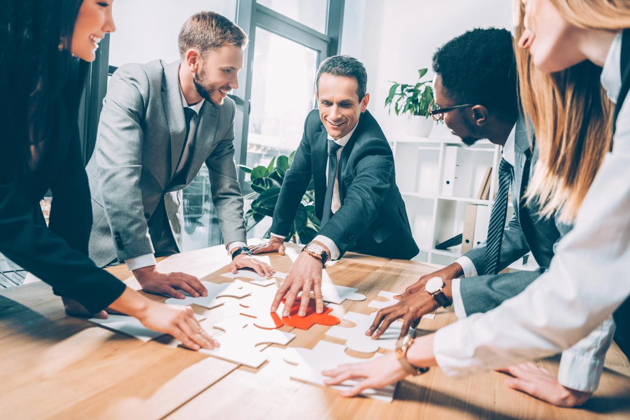 Diverse business team assembling puzzle in conference room